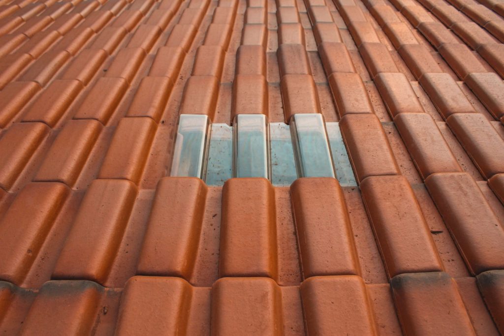 How to Choose the Right Roofing Contractor - A close up shot of rust-colored roofing material with a silver-colored rectangle in the center. Commercial Roof Leaks.