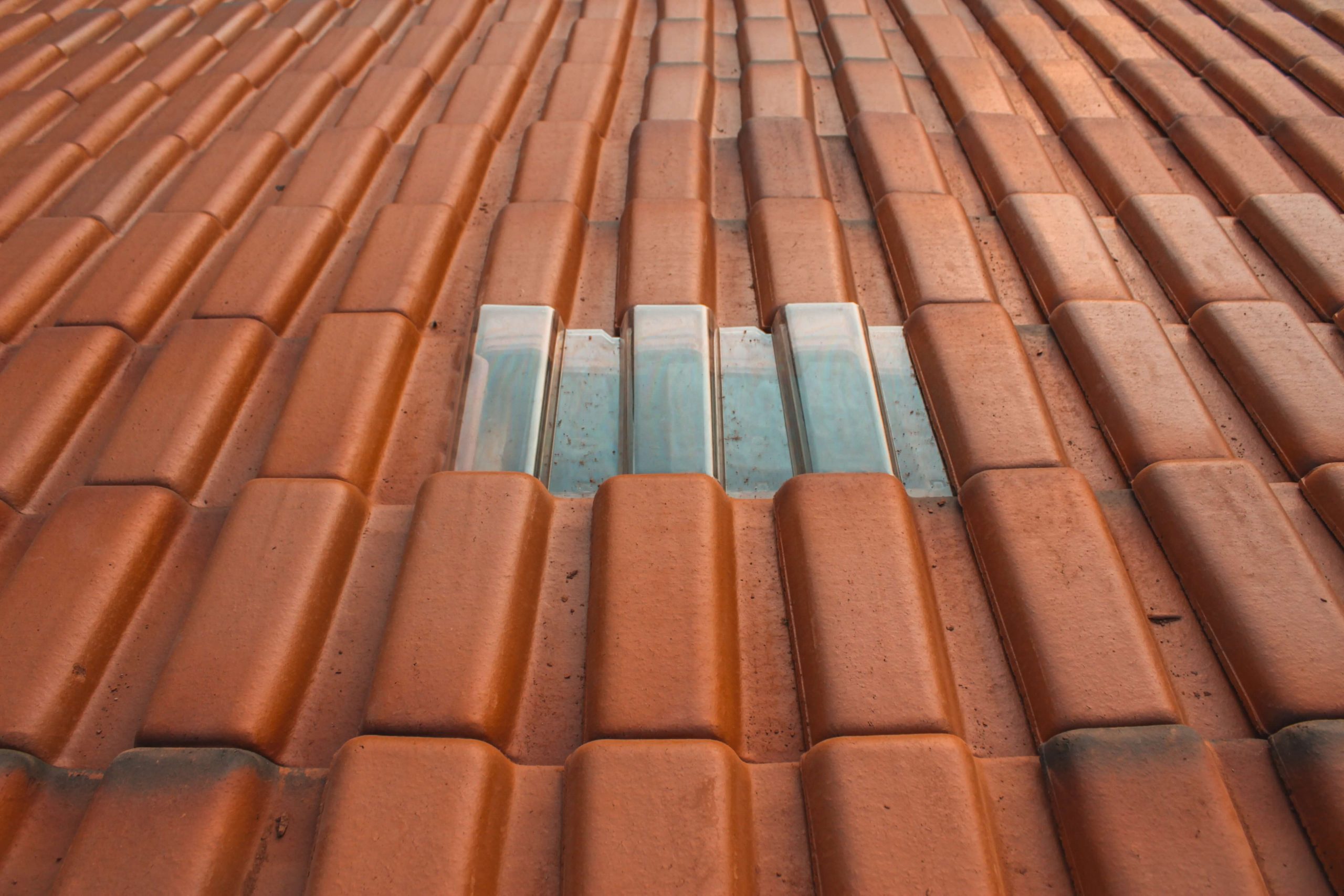 How to Choose the Right Roofing Contractor - A close up shot of rust-colored roofing material with a silver-colored rectangle in the center. Commercial Roof Leaks.
